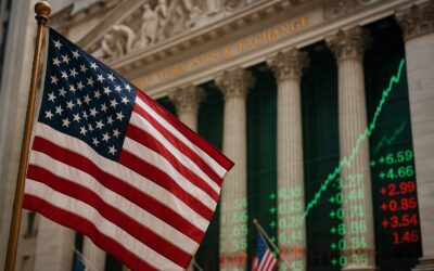 A United States flag waves in front of the New York Stock Exchange building, with green and red stock market numbers and an upward trending chart displayed on a large electronic screen in the background.